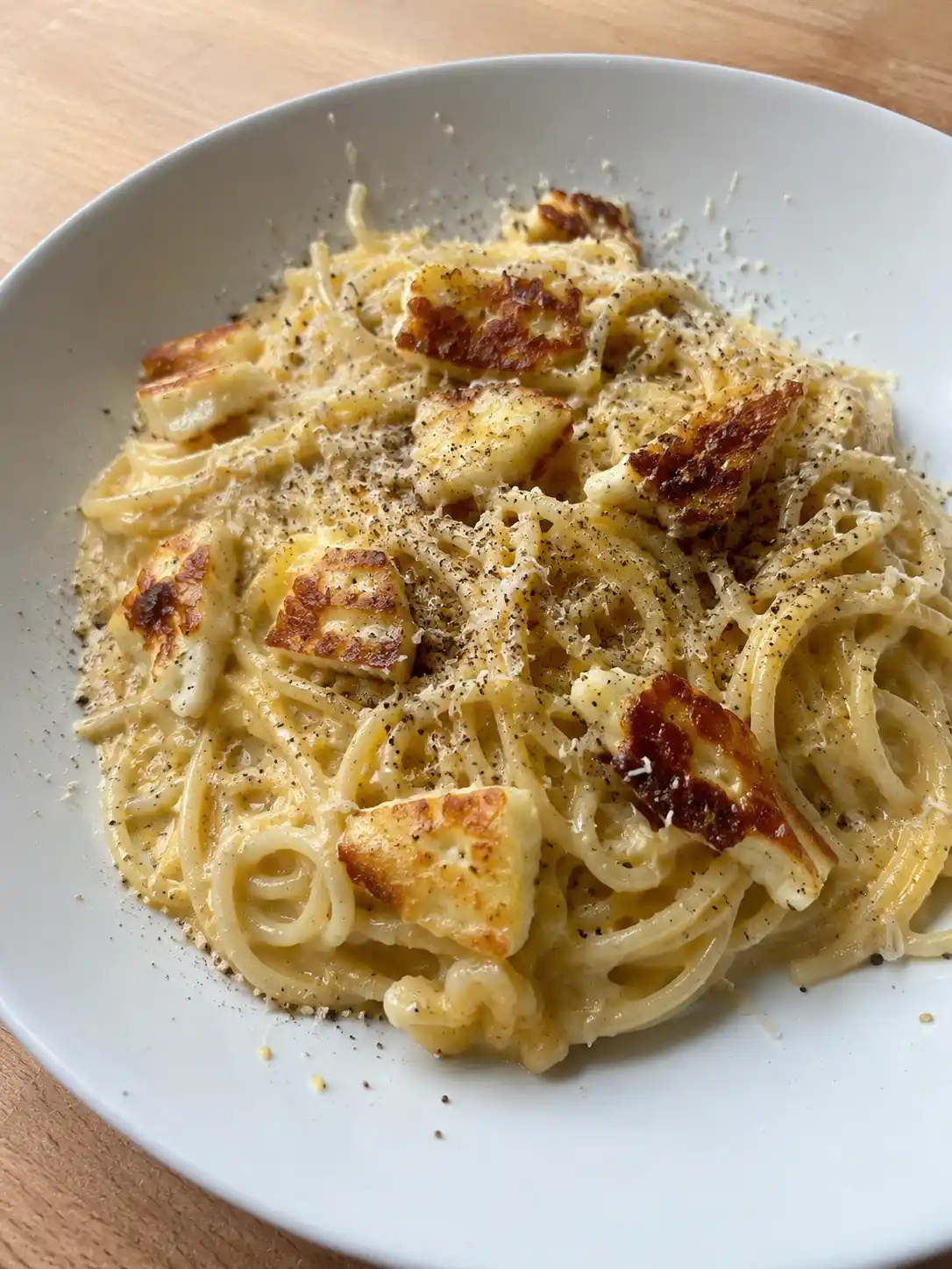 halloumi carbonara på tallrik med spaghetti, gyllenbrun halloumi, krämig ostsås och rikligt med svartpeppar