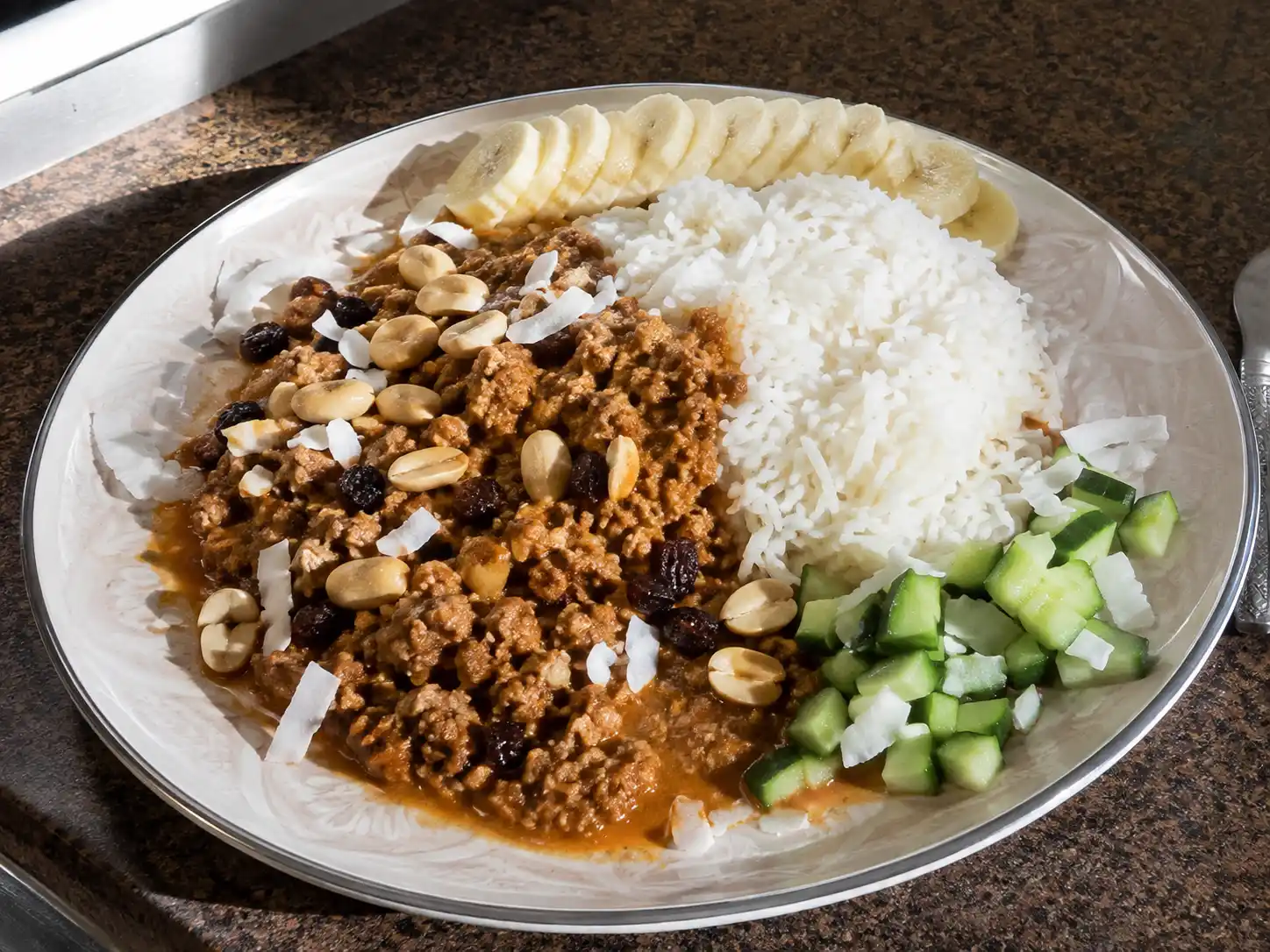köttfärs bombay med krämig tomatsås, ris, skivad banan, gurka, russin, jordnötter och kokos